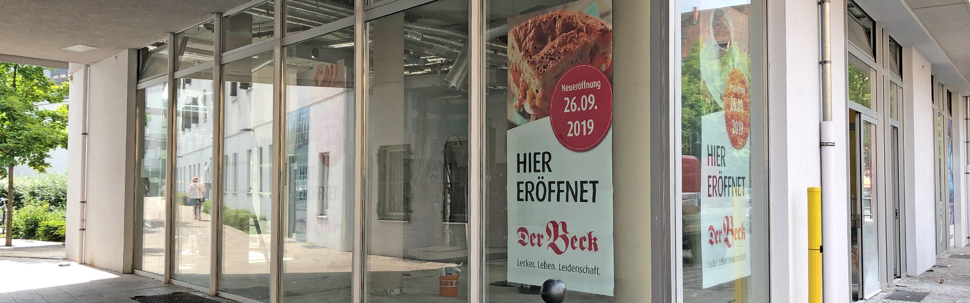 Gebäude mit Neueröffnungs-Plakaten im Fenster 